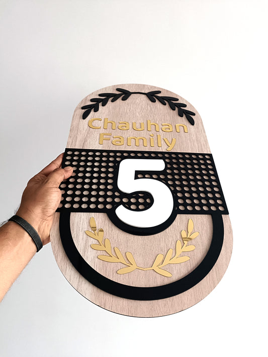 Wooden plaque with 'Chauhan Family' and number '5' on a white background
